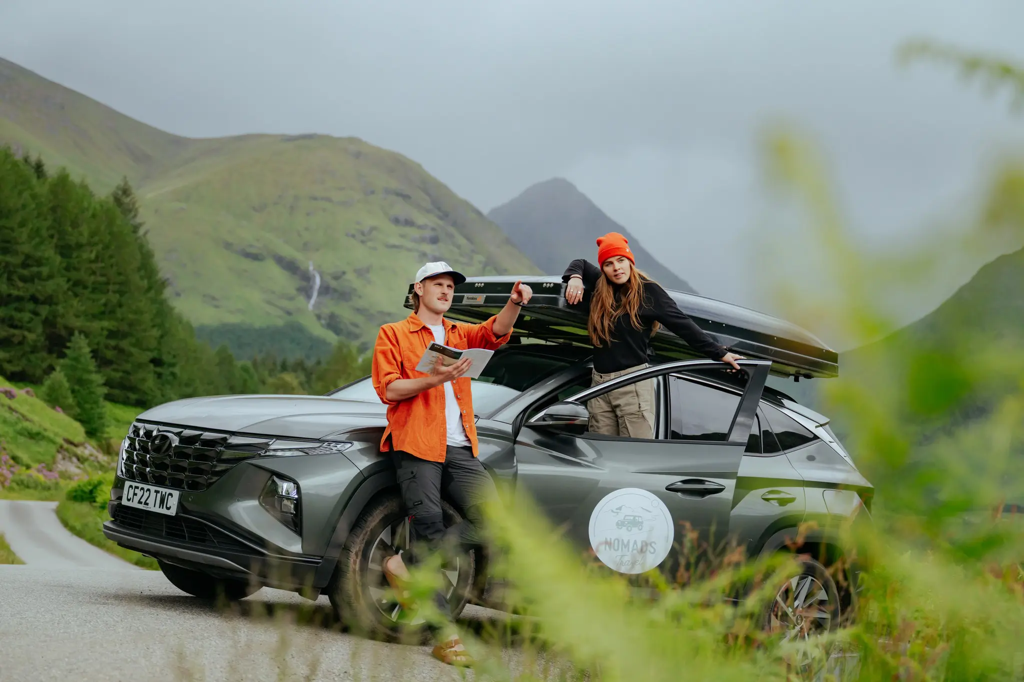 couple with car and roof tent on a road trip in Scotland