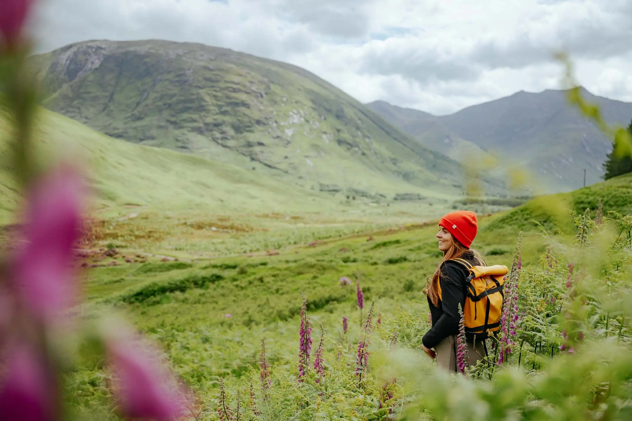 woman hiking in Scottish Highlands with red beanie and yellow backpack