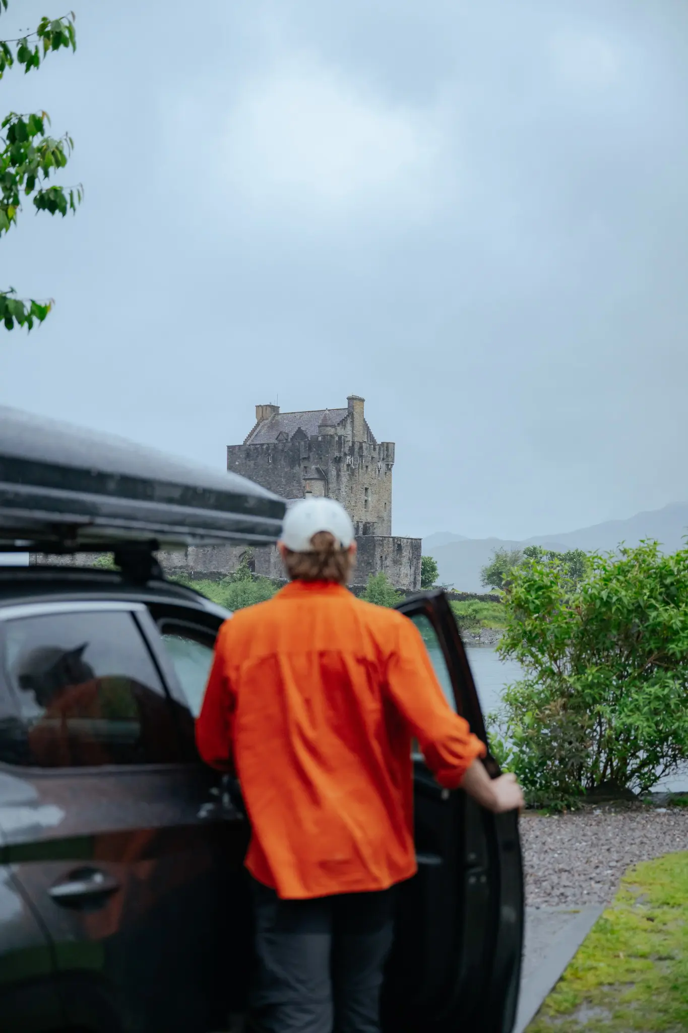 person getting out of car looking at Eilean Donan Castle Scotland
