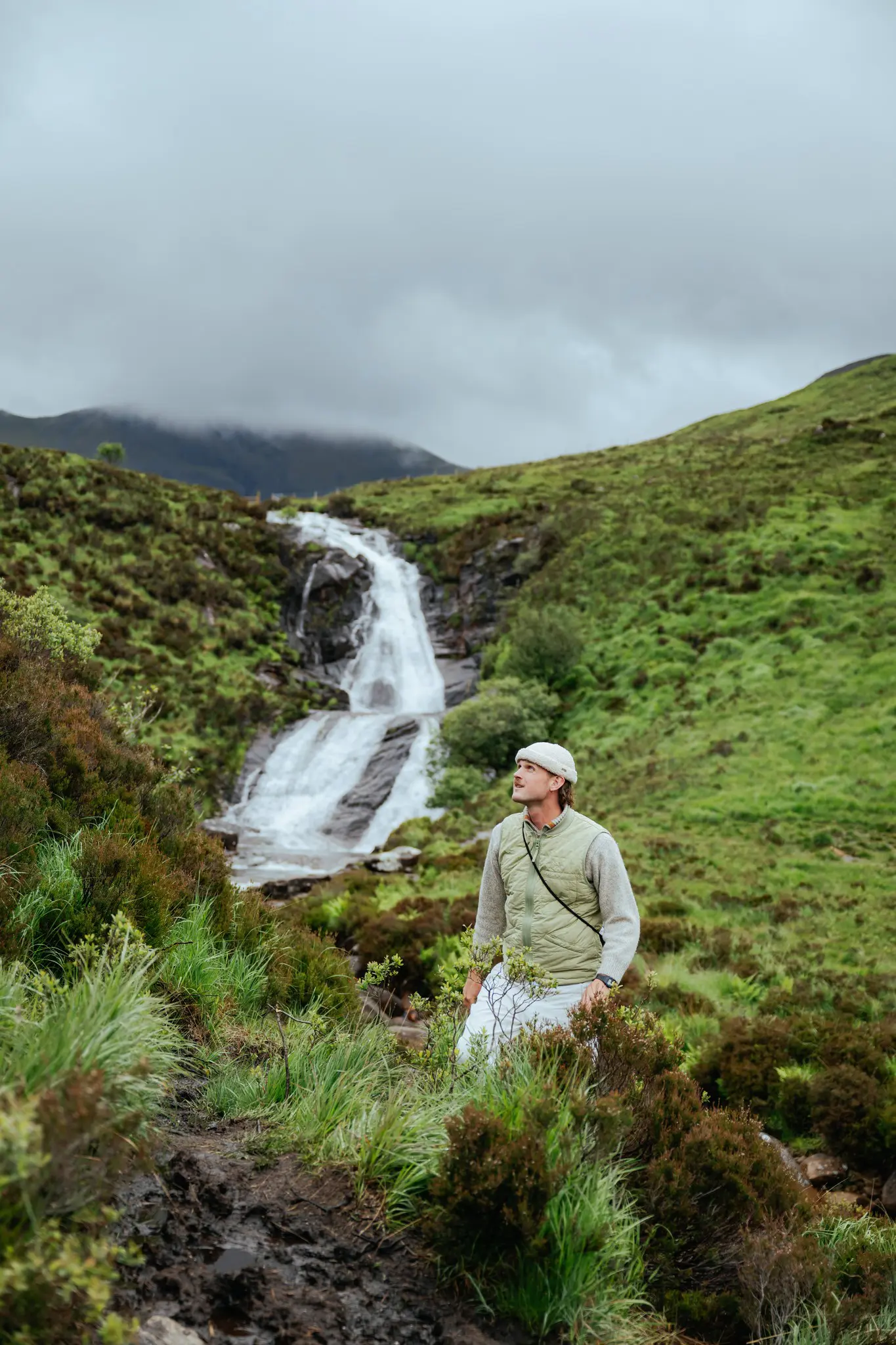 man hiking in scottish highlands looking at waterfall