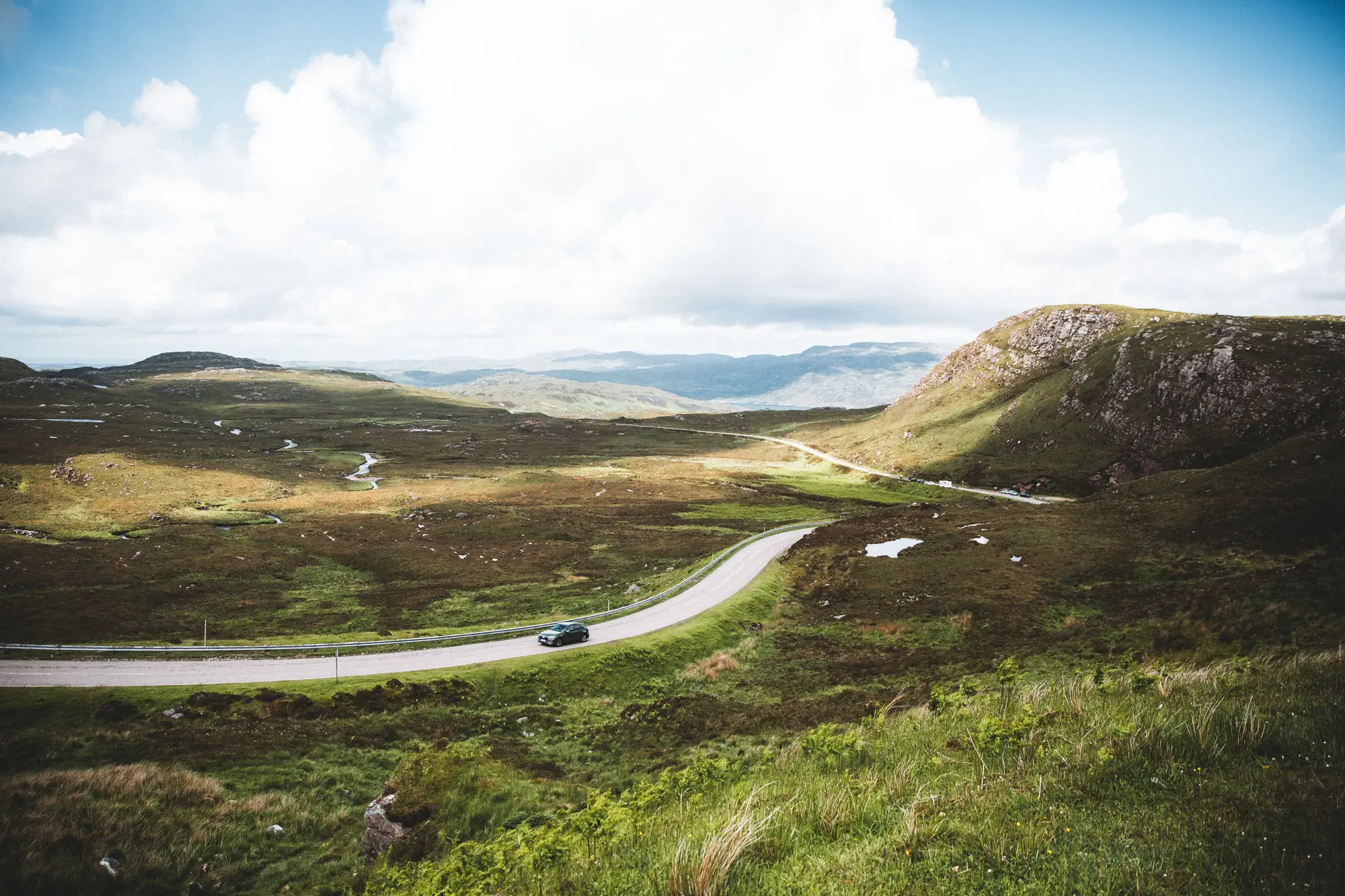 car driving on winding road through Scottish Highlands