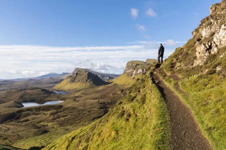 hiker on a trail overlooking the Quiraing landscape on the Isle of Skye