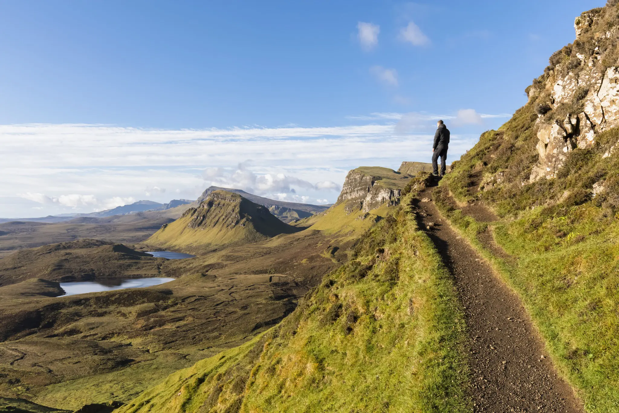 hiker on a trail overlooking the Quiraing landscape on the Isle of Skye