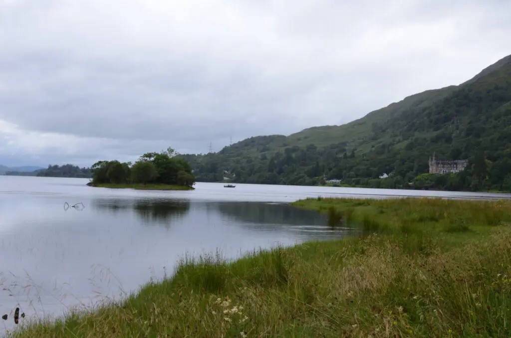 loch landscape with small island, boat, and distant castle