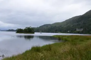 loch landscape with small island, boat, and distant castle