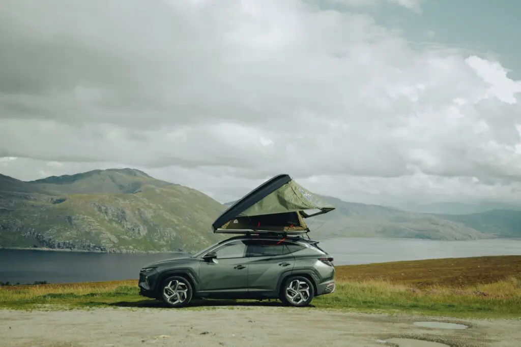 car with rooftop tent parked by a lake in the Scottish Highlands