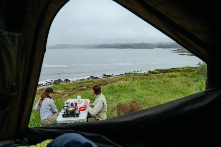 couple camping and cooking breakfast by the sea in Scotland