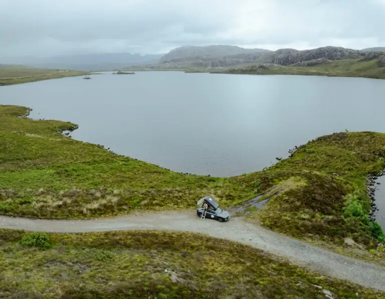 drone shot of campervan with rooftop tent by a Scottish loch
