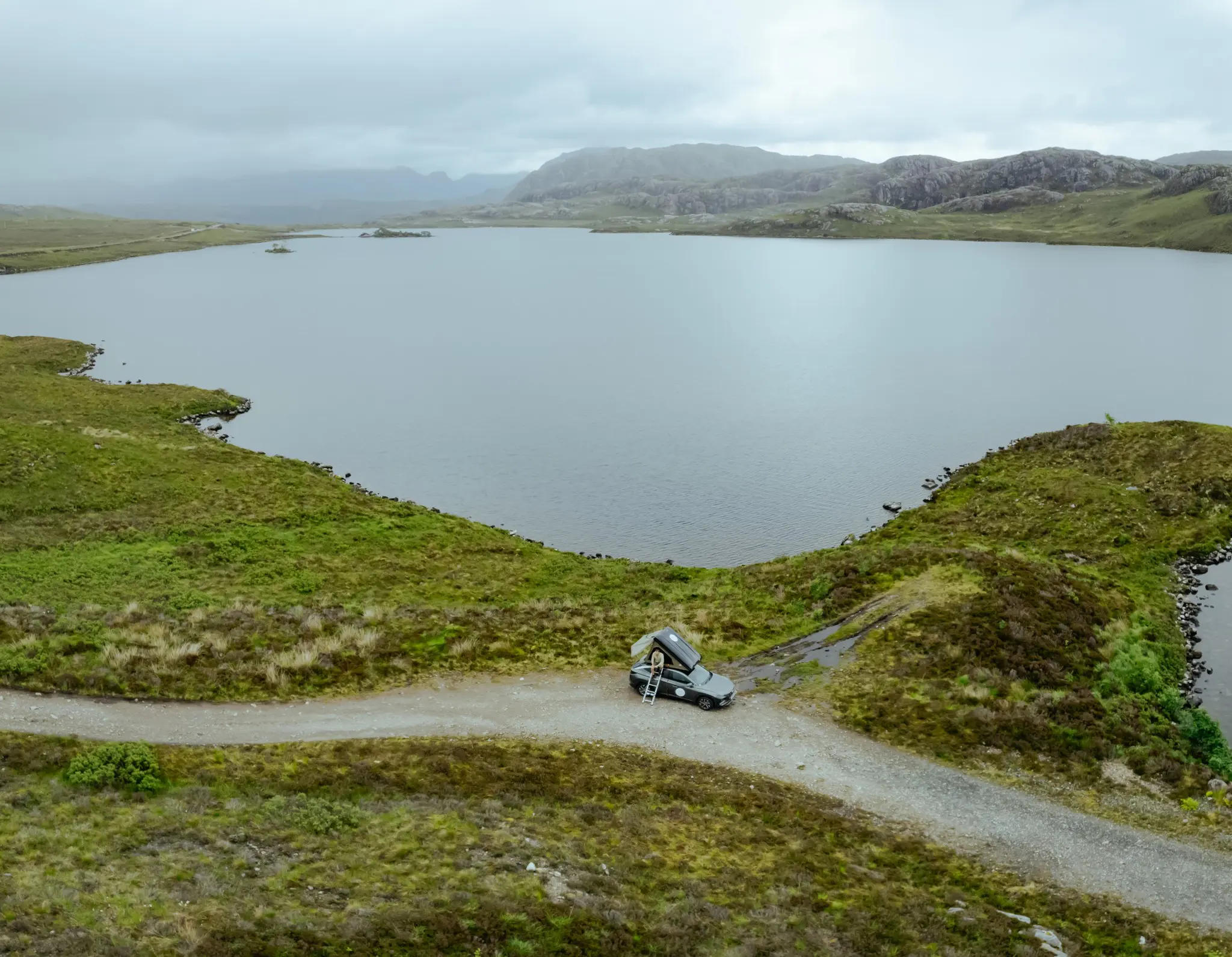 drone shot of campervan with rooftop tent by a Scottish loch