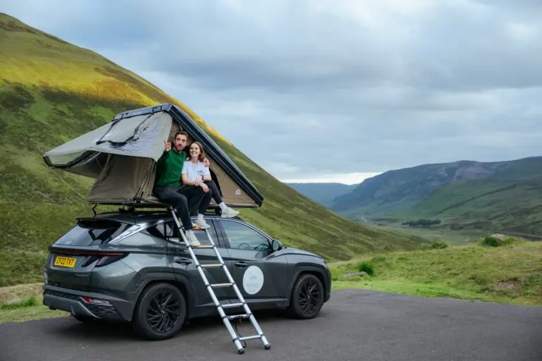 couple on car roof tent in Scottish Highlands