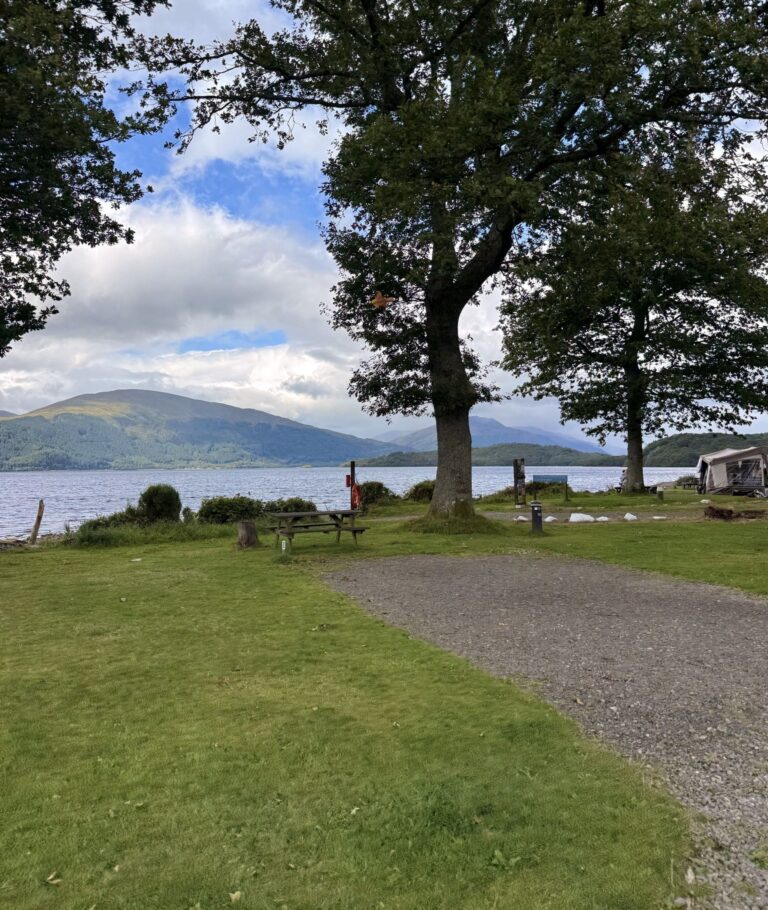 Campingplatz an einem See mit Bergen und Bäumen