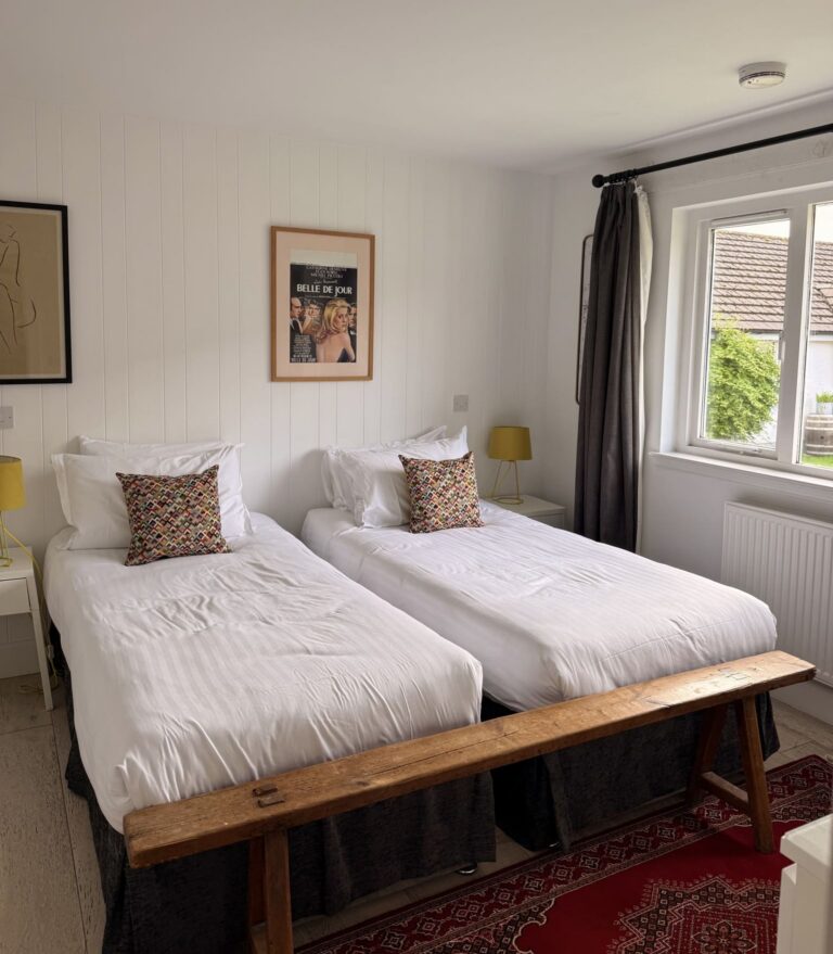 twin bedroom with white beds and a wooden bench